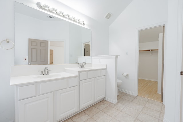 bathroom featuring wood-type flooring, vanity, toilet, and vaulted ceiling