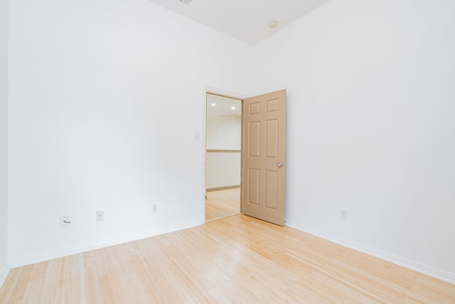 empty room with light wood-type flooring and a high ceiling