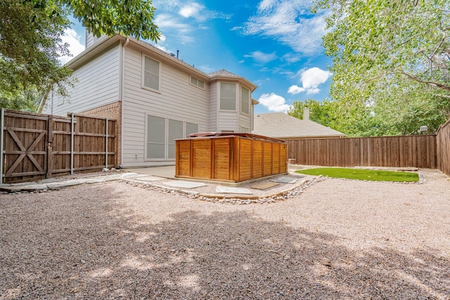 rear view of property with a patio area and a jacuzzi