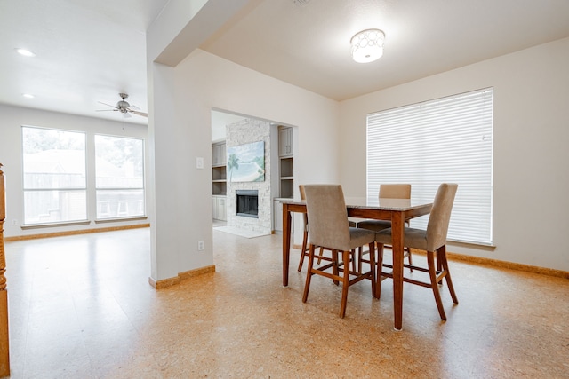 dining room with a fireplace, ceiling fan, and built in shelves