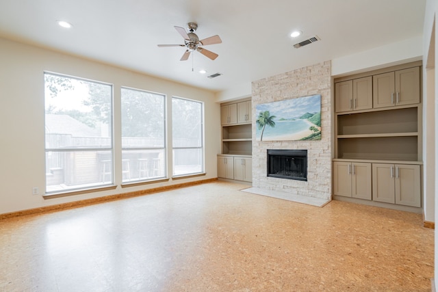 unfurnished living room featuring a stone fireplace, ceiling fan, and built in features