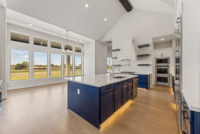 kitchen with blue cabinets, white cabinets, an island with sink, sink, and high vaulted ceiling