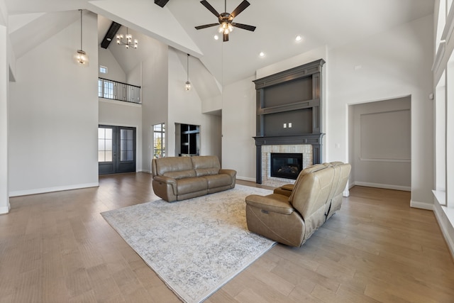 living room with high vaulted ceiling, ceiling fan with notable chandelier, a fireplace, beam ceiling, and hardwood / wood-style flooring