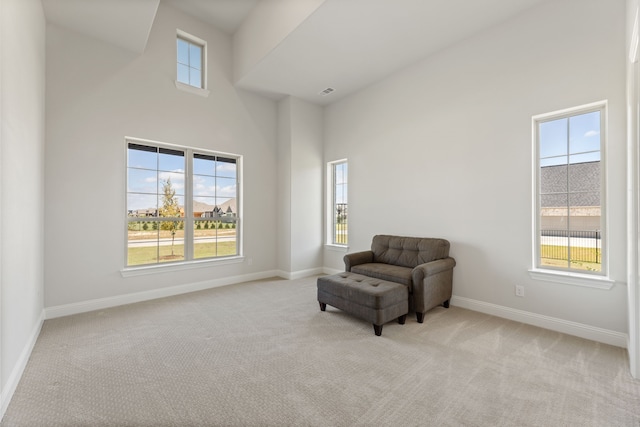 living area with a towering ceiling, light carpet, and a wealth of natural light