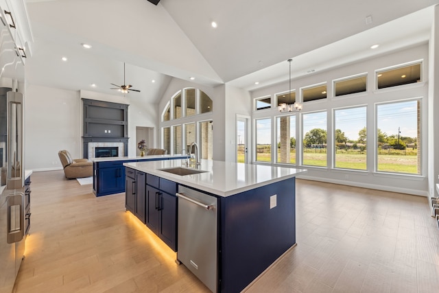 kitchen with sink, a kitchen island with sink, light hardwood / wood-style flooring, high vaulted ceiling, and ceiling fan with notable chandelier