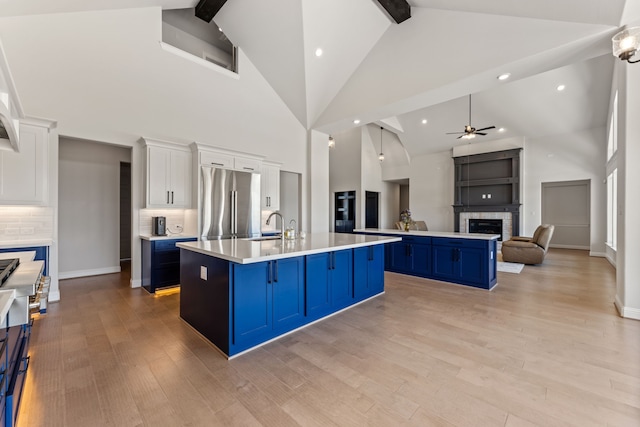 kitchen with an island with sink, a breakfast bar, white cabinets, blue cabinetry, and ceiling fan