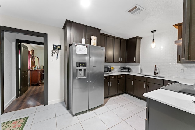 kitchen featuring sink, dark brown cabinets, decorative light fixtures, stainless steel appliances, and light tile patterned flooring