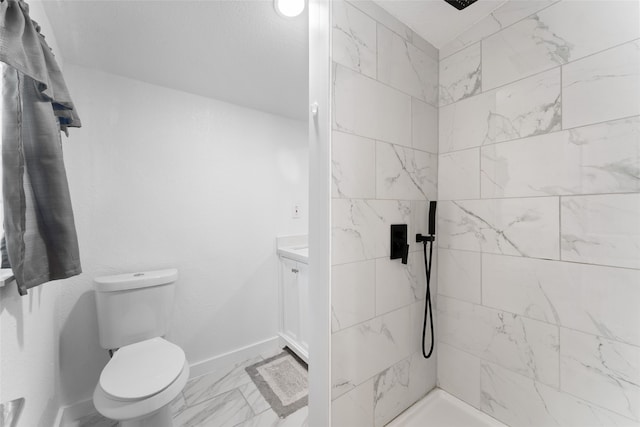 bathroom featuring tiled shower, toilet, and vanity