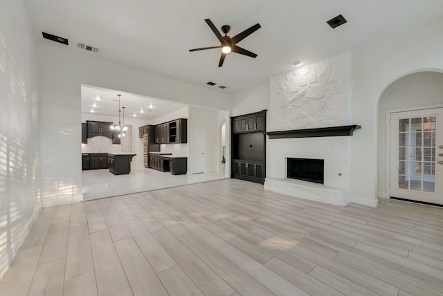 1005 Barre Meadow Ln, Mckinney, TX 75071 - unfurnished living room featuring light wood finished floors, a fireplace, visible vents, and ceiling fan with notable chandelier
