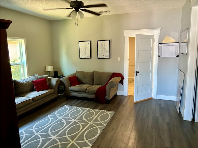 living room with dark wood-type flooring, ceiling fan, and a textured ceiling