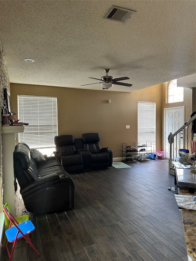 living room with ceiling fan, a textured ceiling, and dark hardwood / wood-style flooring