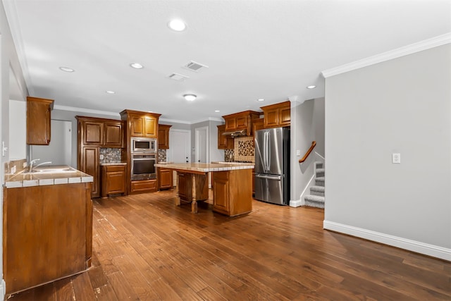 kitchen featuring decorative backsplash, wood-type flooring, appliances with stainless steel finishes, and a kitchen island