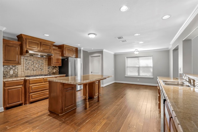 kitchen featuring a breakfast bar, a center island, hardwood / wood-style flooring, and sink