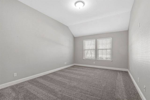 carpeted empty room featuring vaulted ceiling