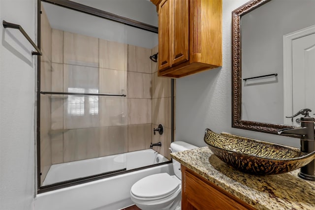 full bathroom featuring combined bath / shower with glass door, vanity, and toilet