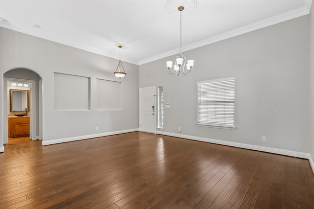 empty room featuring dark hardwood / wood-style floors, a chandelier, and crown molding