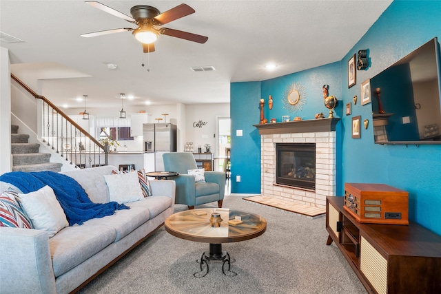 living room with carpet flooring, ceiling fan, and a fireplace