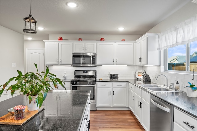 kitchen featuring appliances with stainless steel finishes, backsplash, white cabinetry, and sink