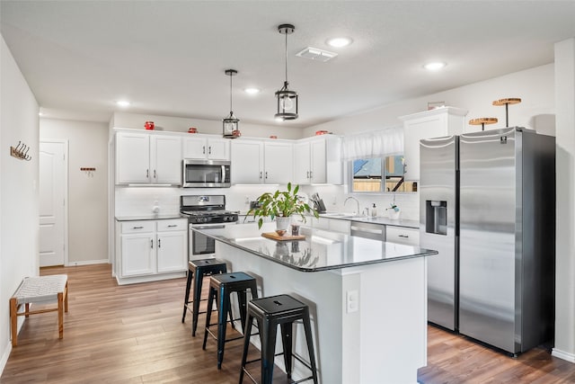 kitchen with white cabinetry, light hardwood / wood-style flooring, a kitchen island, and stainless steel appliances