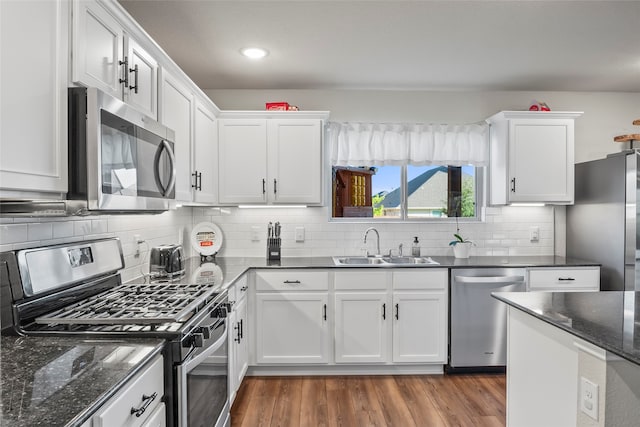 kitchen with dark wood-type flooring, sink, tasteful backsplash, white cabinetry, and stainless steel appliances