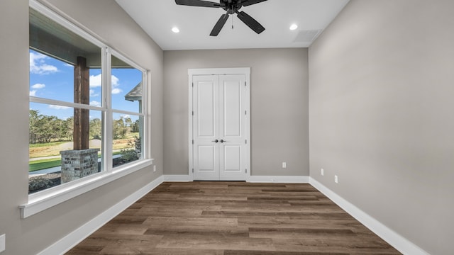 unfurnished bedroom featuring a closet, wood-type flooring, multiple windows, and ceiling fan