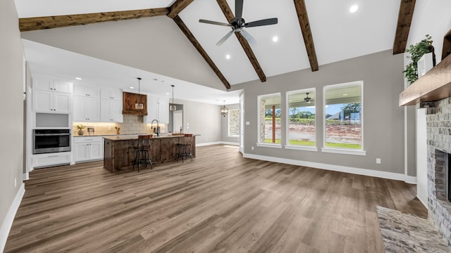 unfurnished living room featuring high vaulted ceiling, hardwood / wood-style floors, ceiling fan, and a fireplace