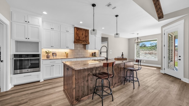 kitchen with sink, an island with sink, and white cabinets