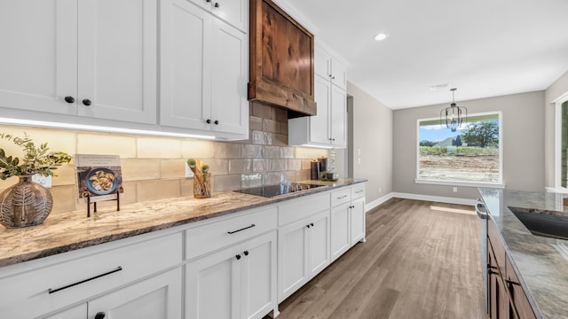 kitchen with black electric stovetop, white cabinetry, light hardwood / wood-style floors, and light stone counters