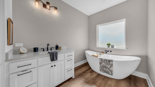 bathroom with wood-type flooring, vanity, a bathing tub, and lofted ceiling