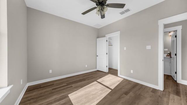 unfurnished bedroom featuring ceiling fan, lofted ceiling, dark wood-type flooring, and a walk in closet