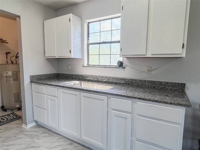 kitchen with white cabinets, sink, and water heater