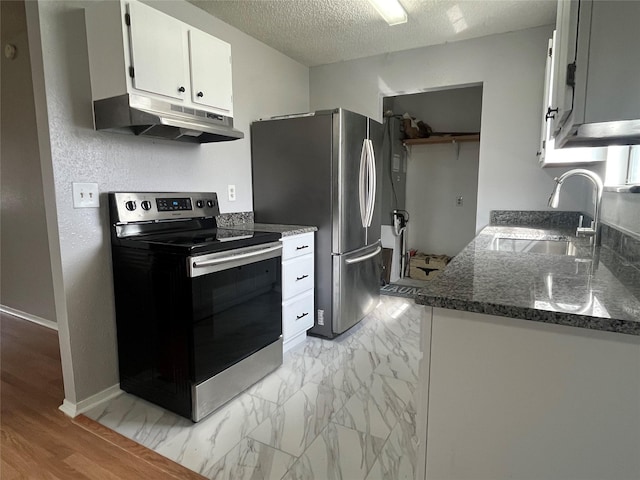 kitchen with appliances with stainless steel finishes, marble finish floor, a textured ceiling, under cabinet range hood, and a sink