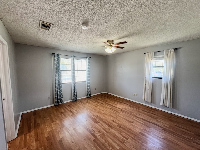 empty room featuring hardwood / wood-style floors, plenty of natural light, ceiling fan, and a textured ceiling