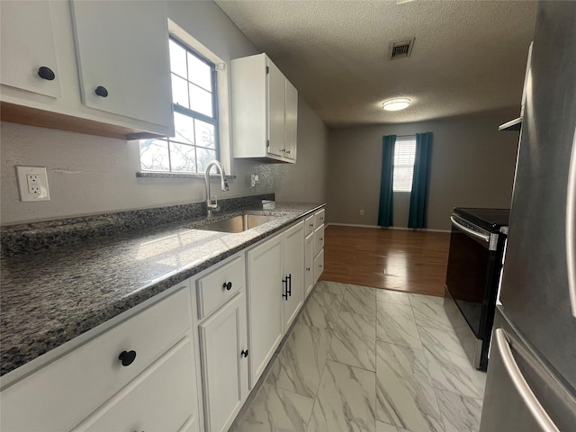 kitchen featuring a textured ceiling, a sink, visible vents, marble finish floor, and appliances with stainless steel finishes