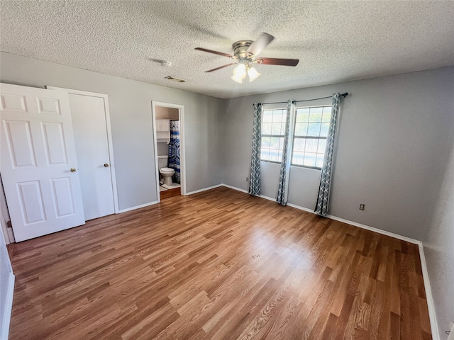 unfurnished bedroom featuring connected bathroom, ceiling fan, hardwood / wood-style floors, and a textured ceiling