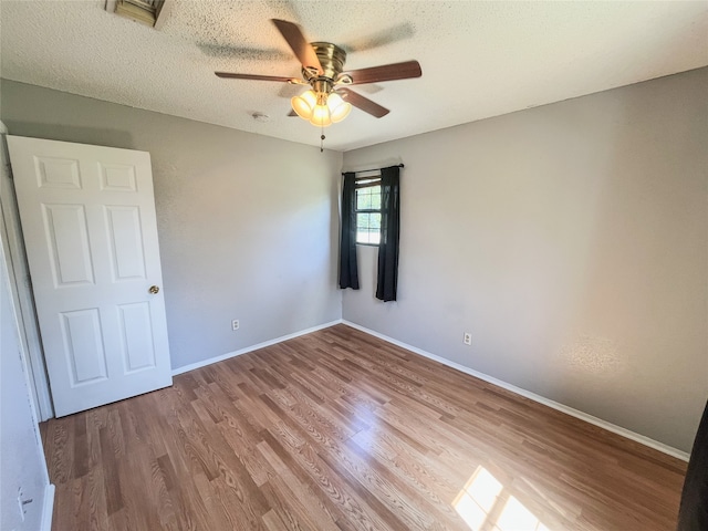 unfurnished room with ceiling fan, a textured ceiling, and light wood-type flooring