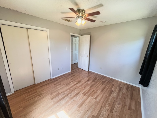 unfurnished bedroom with ceiling fan, a closet, a textured ceiling, and light wood-type flooring