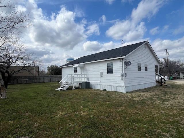 back of property with a yard, central AC unit, and fence