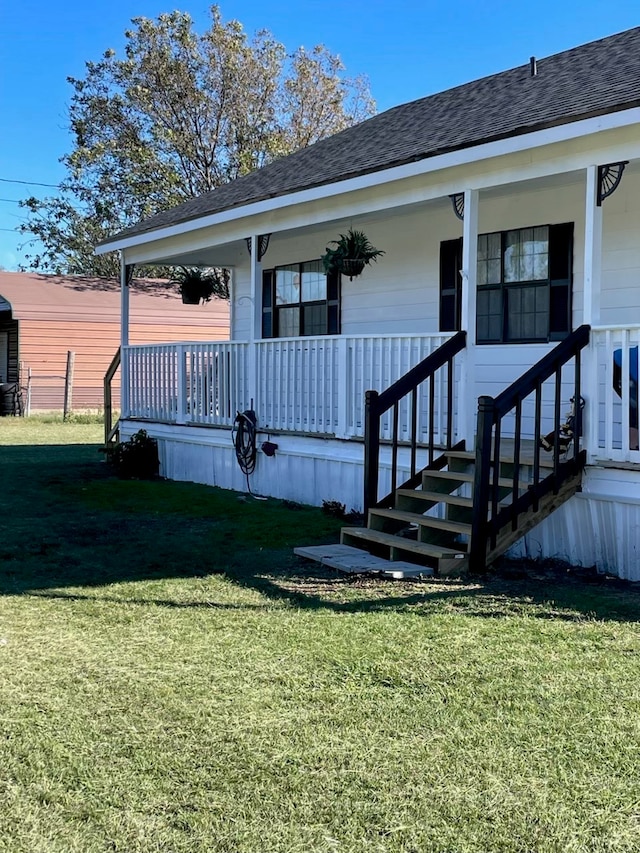 view of exterior entry featuring a lawn and a porch