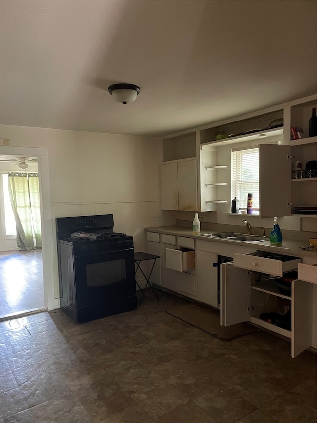 kitchen with white cabinetry, black gas range oven, and sink