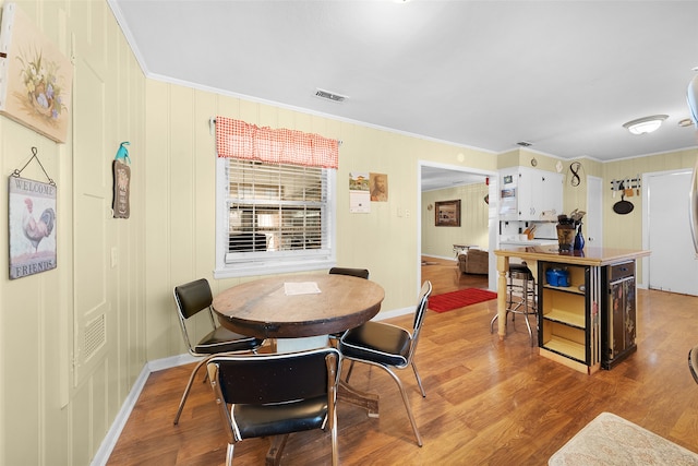 dining space featuring ornamental molding and light hardwood / wood-style floors