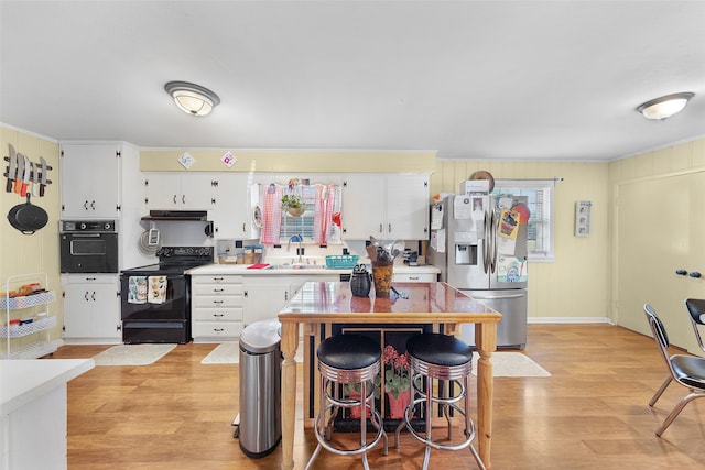 kitchen with black appliances, light hardwood / wood-style floors, sink, and white cabinets