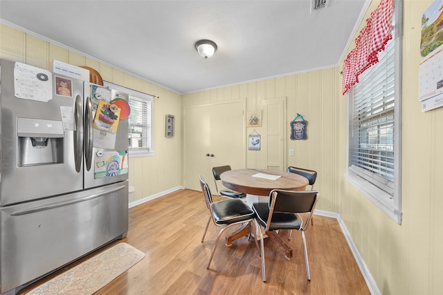 dining space featuring ornamental molding, light wood-type flooring, and a healthy amount of sunlight