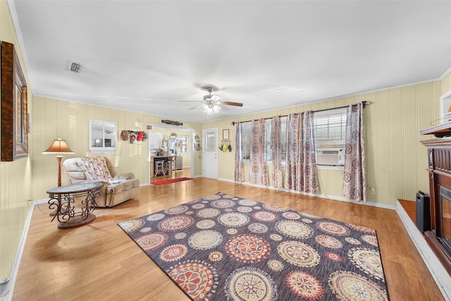 living room with ceiling fan, cooling unit, and light hardwood / wood-style flooring