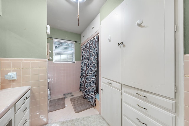 bathroom with walk in shower, vanity, tile walls, and tile patterned floors