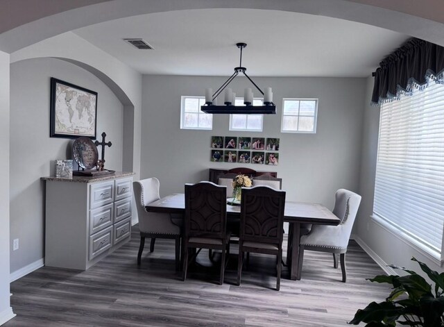 dining room with baseboards, wood finished floors, visible vents, and an inviting chandelier