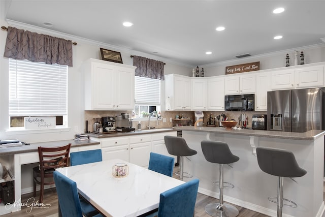 kitchen with a center island, dark hardwood / wood-style floors, stainless steel refrigerator with ice dispenser, white cabinetry, and ornamental molding