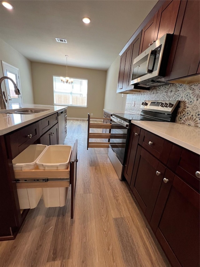 100 Levi Dr, Cleburne, TX 76031 - kitchen featuring appliances with stainless steel finishes, a sink, wood finished floors, a chandelier, and recessed lighting