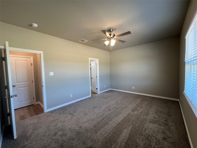 unfurnished bedroom with dark colored carpet and ceiling fan