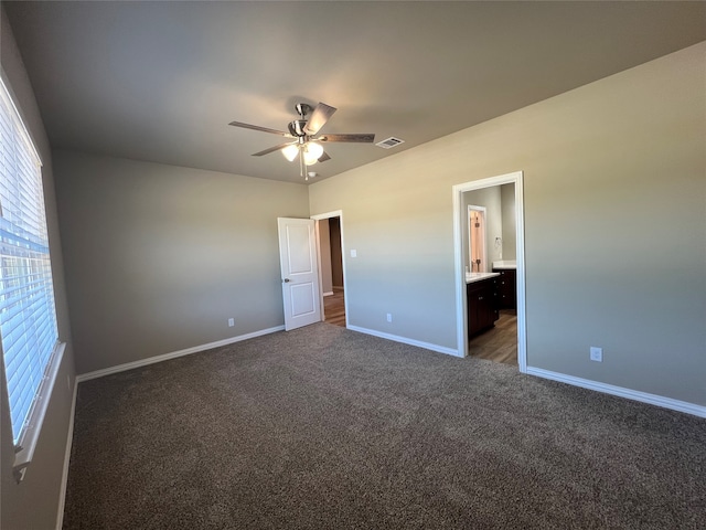 unfurnished bedroom featuring connected bathroom, ceiling fan, and dark carpet